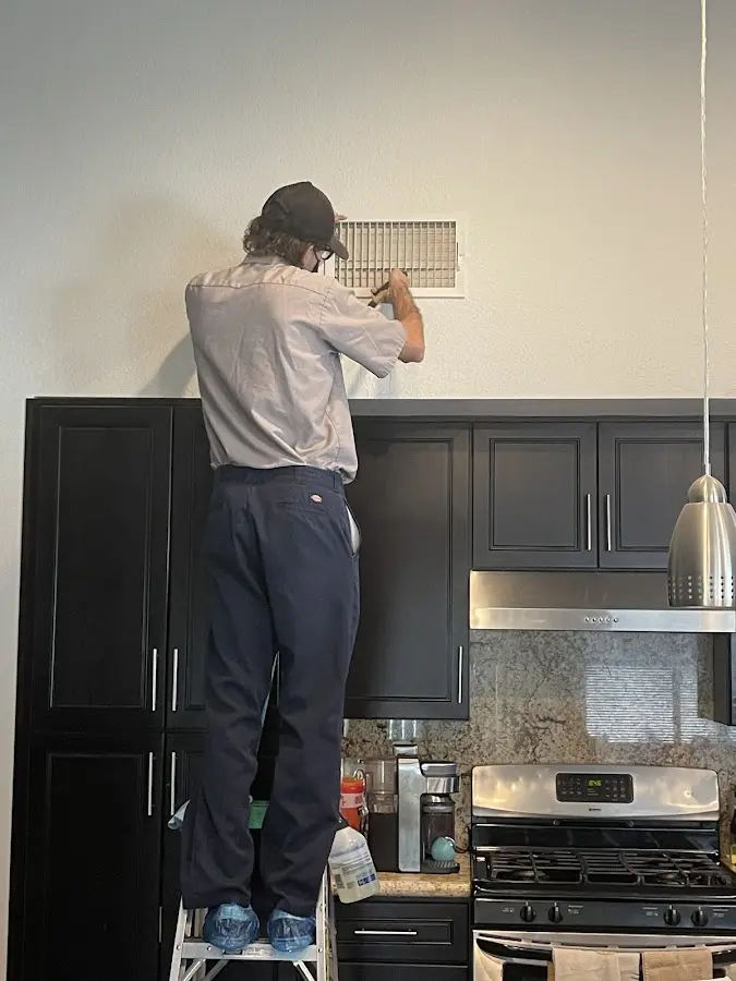 Technician inspecting an air vent during HVAC service in Delphos
